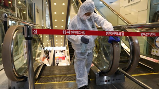 A worker sprays antiseptic solution on escalator handles at a department store in Seoul, South Korea.