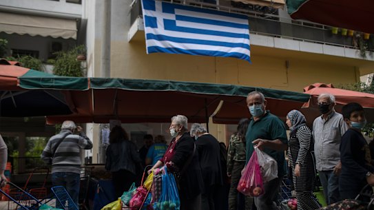 People wearing face masks to curb the spread of coronavirus walk, at an open air fruit and vegetable market in Petralona district of Athens, Wednesday, Nov. 4, 2020. Greece, on Tuesday reported a new record of over 2,000 daily COVID-19 infections, and a further 13 deaths – which bring the overall death toll to over 650(AP Photo/Petros Giannakouris)