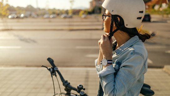 Young woman putting her helmet, preparing for the bike ride The AGE  12 June, 2021 
Young woman putting on helmet to bike ride. Generic Bike bicycle ride Istock Image 