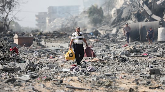 Palestinians walk by the buildings destroyed in the Israeli bombardment on al-Zahra, on the outskirts of Gaza City. 