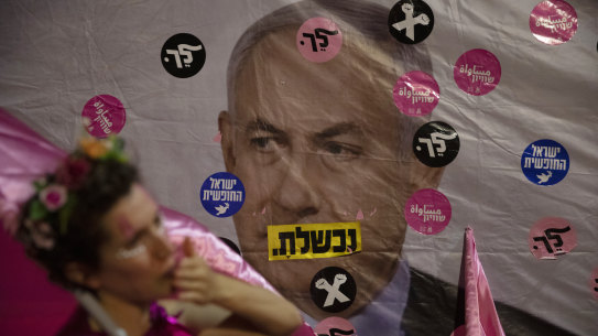 An Israeli protester wears pink during a demonstration against Israeli Prime Minister Benjamin Netanyahu outside his official residence in Jerusalem on Saturday, June 12, 2021. Hebrew reads: “You failed”,” Israel free” and “Leave”.