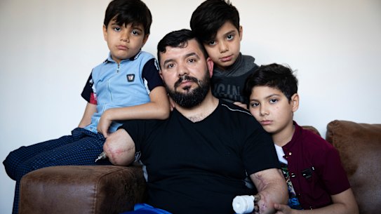 Eight-year-old twins Ahmed and Mohammed al-Shnen and 10-year-old Ali (right) with their father at his home. 
