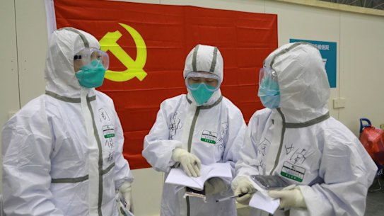 Back when it was a domestic story. Medical workers discuss patients' treatment near a Communist Party flag at the "Wuhan Living Room" temporary hospital in Wuhan in early February. 