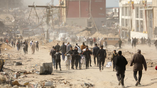 Palestinians carry bags of flour received from an aid truck that arrived in the west of Gaza City on March 6.