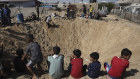 Palestinian children sit at the edge of a crater after an Israeli airstrike in Khan Younis.
