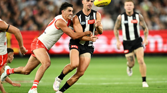 Scott Pendlebury of the Magpies passes is tackled by Justin McInerney of the Swans.