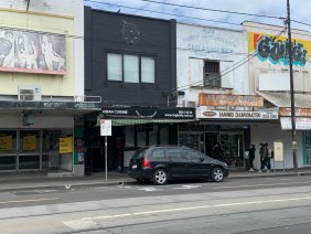 The Sydney Road venue in Coburg (centre) that’s been listed as a COVID-19 exposure site has a ‘for lease’ sign and material across the windows, unoccupied.