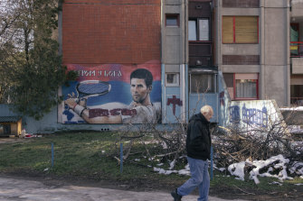 A Belgrade resident walks past a mural of deported tennis star Novak Djokovic.