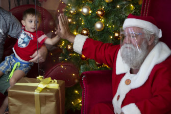 No lap: A child greets Santa through a plastic shield in a shopping centre in Johannesburg, South Africa.