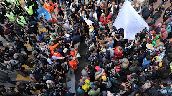 Migrants listen to Mexican authorities as they join a small group of migrants trying to cross the border at the Chaparral crossing in Tijuana on Thursday.