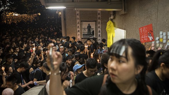Demonstrators attend a vigil for a man who fell to his death after hanging a protest banner over a roadway on Saturday.
