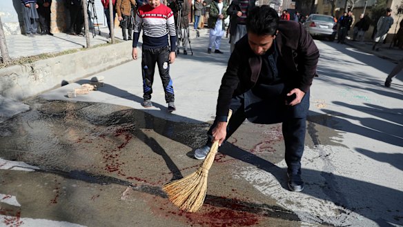 An Afghan man sweeps blood off a Kabul street after a Taliban attack on two female judges in January.