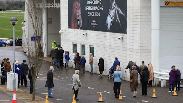 Members of the public queue to receive the Oxford-AstraZeneca coronavirus vaccine at a mass vaccination centre at a Epsom racecourse in England.