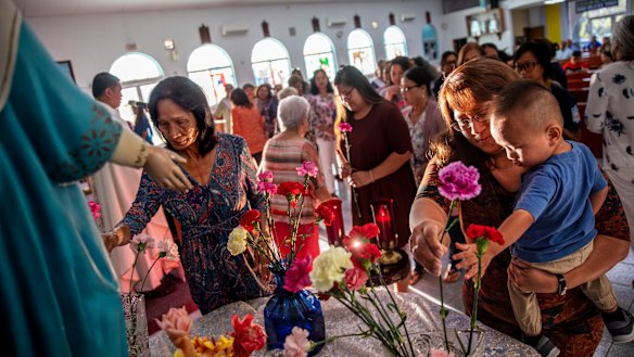 Jeanie Bamba holds her grandson, Jayce, as they lay flowers at Immaculate Heart of Mary Catholic Church in Toto, Guam, on Mother's Day. Catholicism is deeply engrained in Chamorro culture.