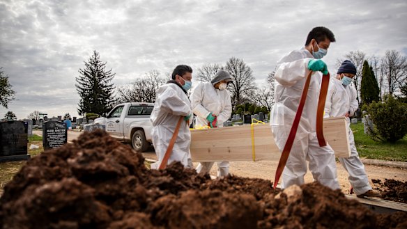 Gravediggers in New York set down the casket of a COVID-19 victim, who was buried without family.