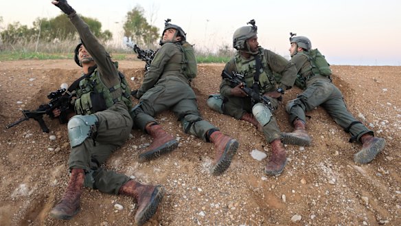 Israeli soldiers take cover near the Gaza border on Monday as fighter jets were dispatched to strike in Gaza.