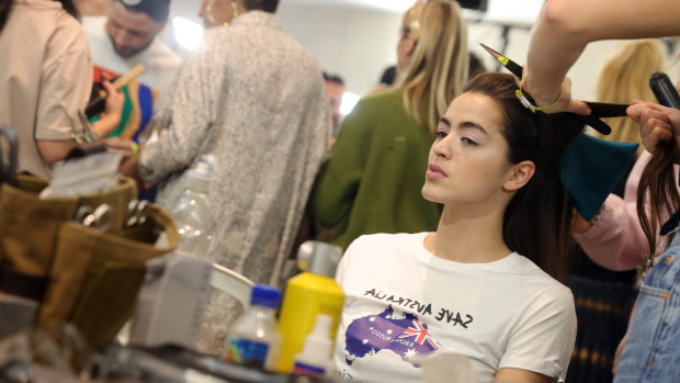 A model wearing a 'Save Australia' bushfire awareness T-shirt has her make-up done backstage before the Ralph & Russo show at Paris Couture Week.