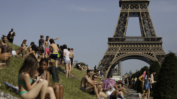 People enjoy the sun on the Trocadero gardens near the Eiffel Tower in Paris.