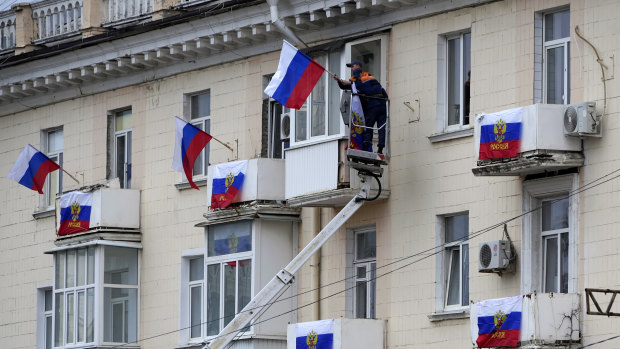 Workers hang Russian flags at an apartment building in Luhansk, Luhansk People’s Republic controlled by Russia-backed separatists, eastern Ukraine.