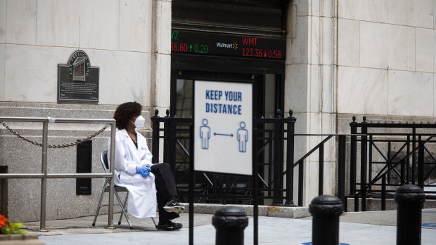 A healthcare worker sits in front of an entrance to the New York Stock Exchange: Optimism about progress on COVID vaccines have buyoed stocks.