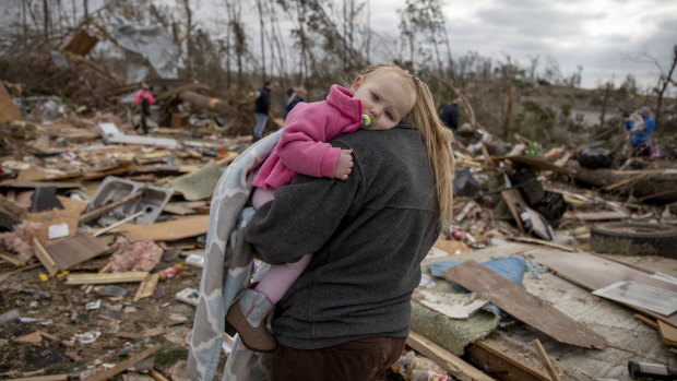 Megan Anderson carries her 18-month-old daughter Madilyn through the debris of her uncle and aunt's home.