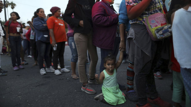 Central American migrants, as part of the Central American caravan trying to reach the United States, wait to receive donated dinner downtown in Mexicali, Mexico.