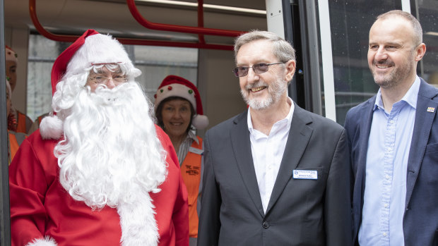 Santa, , St Vincent de Paul Society ACT president Warwick Fulton, and ACT Chief Minister Andrew Barr next to the tram in Gungahlin.