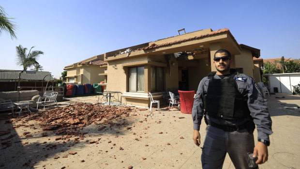 A policeman stands in front of a house hit by a rocket fired from Gaza Strip in Netivot, Israel.