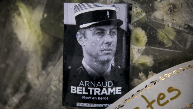 A photo of Lieutenant Colonel Arnaud Beltrame placed on a bunch of flowers at the main gate of the Police headquarters in Carcassonne.