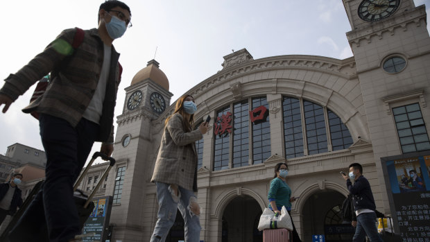 Travellers walk past Hankou railway station on the eve of it resuming outbound traffic in Wuhan.