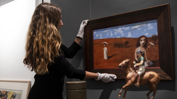 Madeleine Norton straightens the Gary Shead painting "Bettany’s Book" at the Leonard Joel auction house in Sydney.