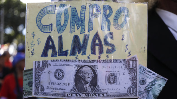 Fake US dollar bills stapled to a sign with the message: "I buy souls" at a pro-government demonstration.