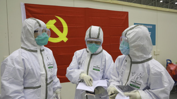 Back when it was a domestic story. Medical workers discuss patients' treatment near a Communist Party flag at the "Wuhan Living Room" temporary hospital in Wuhan in early February. 