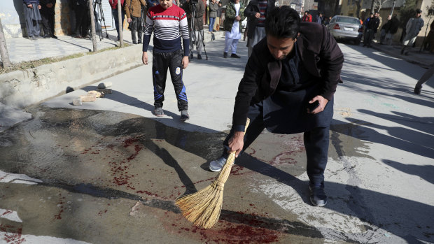 An Afghan man sweeps blood off a Kabul street after a Taliban attack on two female judges in January.