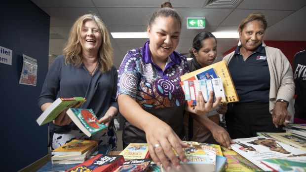 From left, The Smith Family office manager Robin Jarvis, Mikaila McEwan, Sarah Kennedy, and Smith Family program manager Karen Parter look through books at the Woden office on Thursday.