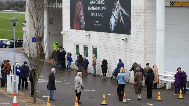 Members of the public queue to receive the Oxford-AstraZeneca coronavirus vaccine at a mass vaccination centre at a Epsom racecourse in England.