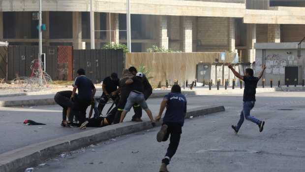 A supporter of Hezbollah and Amal Movement party is helped after being injured near the Justice Palace in Beirut along a former civil war front line between Muslim Shiite and Christian areas in Beirut. 