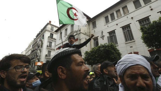 A man holds an Algerian flag while Algerians demonstrate to mark the second anniversary of the Hirak movement.