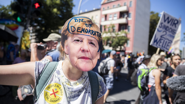 A woman wears a Angela Merkel mask with the inscription “Bye bye democracy” at a demonstration against the Coronavirus restrictions in Berlin.