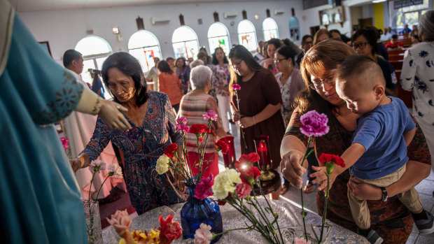 Jeanie Bamba holds her grandson, Jayce, as they lay flowers at Immaculate Heart of Mary Catholic Church in Toto, Guam, on Mother's Day. Catholicism is deeply engrained in Chamorro culture.