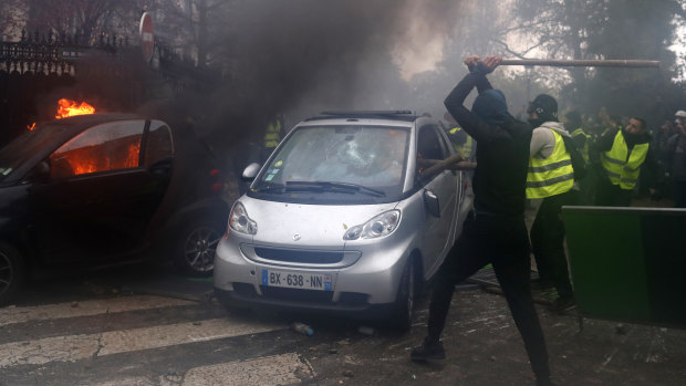 Hooded demonstrators smash a car during a demonstration in Paris on Saturday.