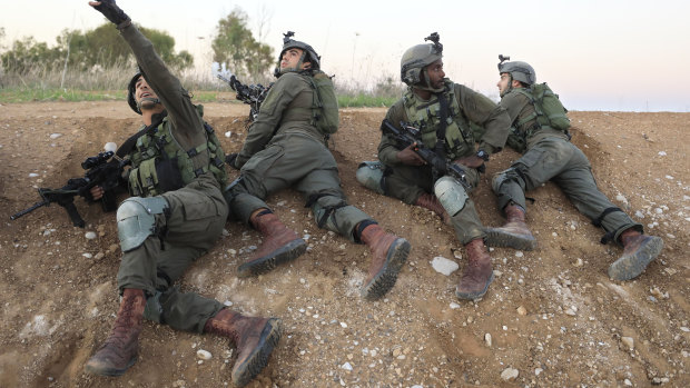 Israeli soldiers take cover near the Gaza border on Monday as fighter jets were dispatched to strike in Gaza.