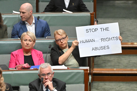Greens Senator Janet Rice holds a sign as Philippines President Ferdinand Marcos Jr speaks in parliament.