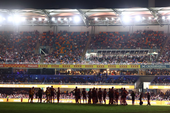 Players wait on field as power goes out during the round two AFL match between Brisbane Lions and Melbourne Demons at The Gabba,