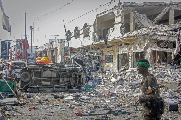 A Somali soldier walks through the scene of a double car-bomb attack in Mogadishu, Somalia.