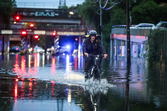 A man rides his bike through floodwater on Lloyd Street in Kensington.