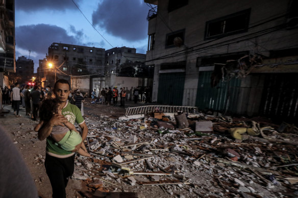 A man carries his child to safety as Israel launches air strikes over the Gaza Strip. 