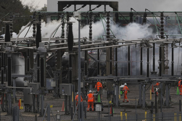 Workers are seen as smoke rises from the North Hyde electrical substation, which caught fire.