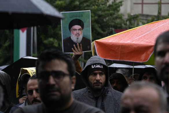 An Iranian demonstrator holds up a poster of slain Hezbollah leader Hassan Nasrallah in a gathering to support Hezbollah in Tehran on Saturday.