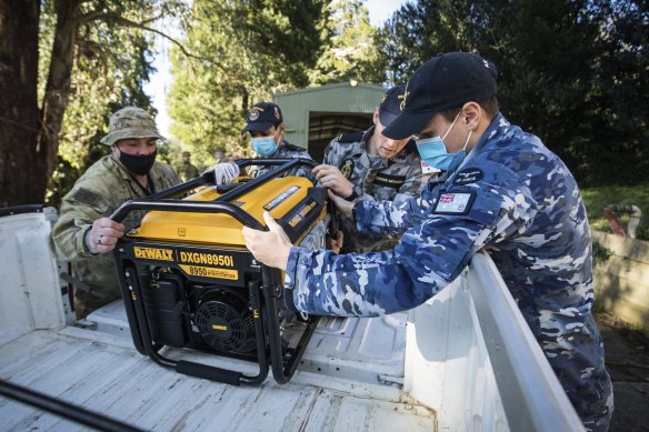 Members of the ADF prepare to load generators to distribute to residents in the storm-ravaged Dandenong Ranges last Sunday.